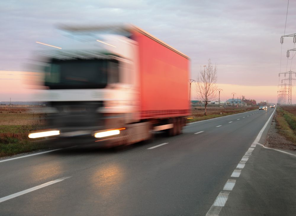 A lorry speeds past the camera at sunset.